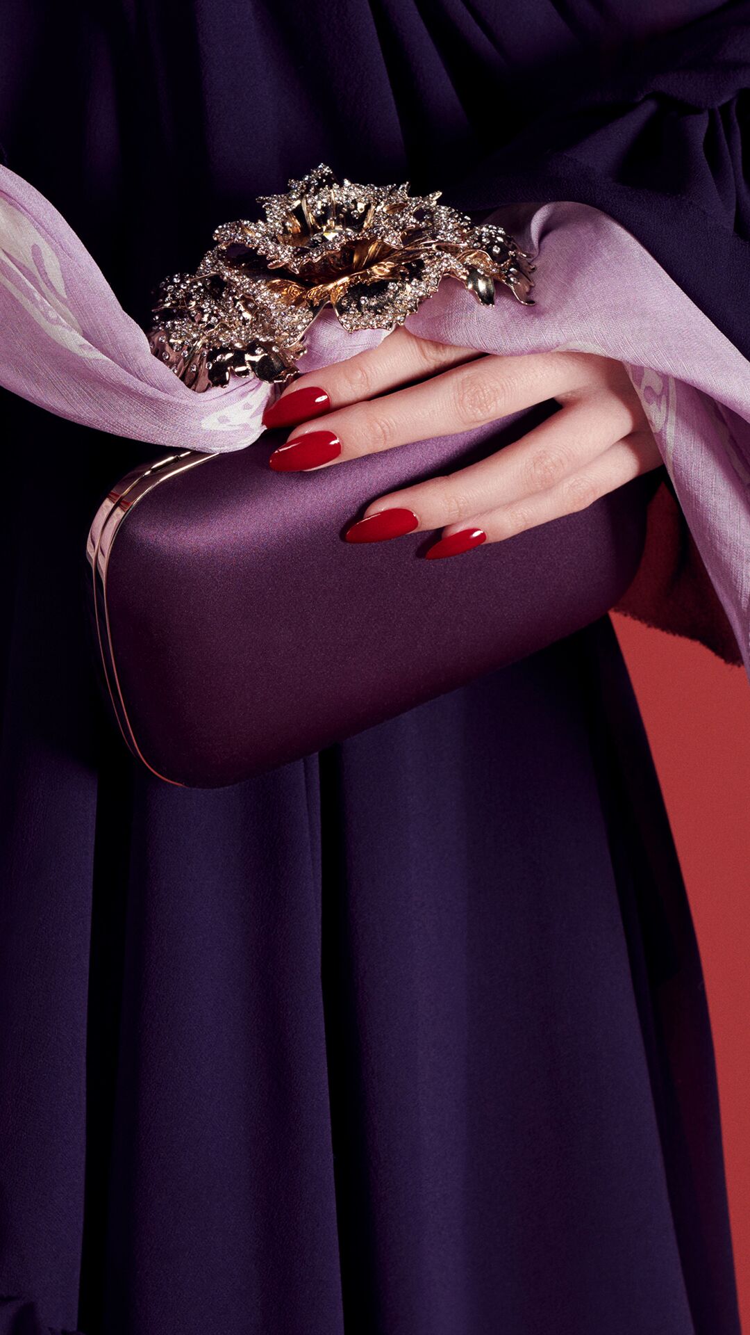 Model carrying a purple knuckle clutch and lilac McQueen skull scarf